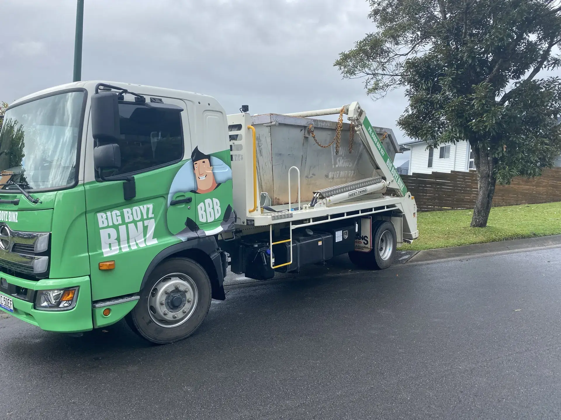 Big Boyz Binz truck carrying a skip bin along a residential street in Cairns