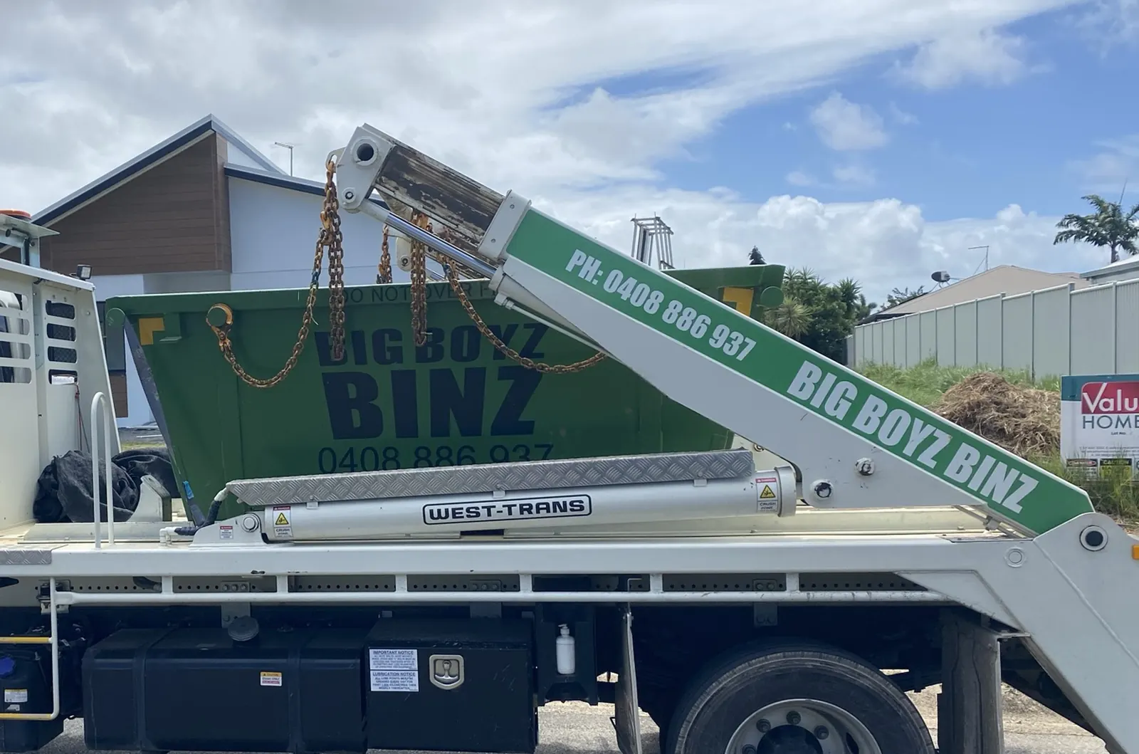 Big Boyz Binz truck lifting a loaded skip bin onto the tray to leave a Cairns site